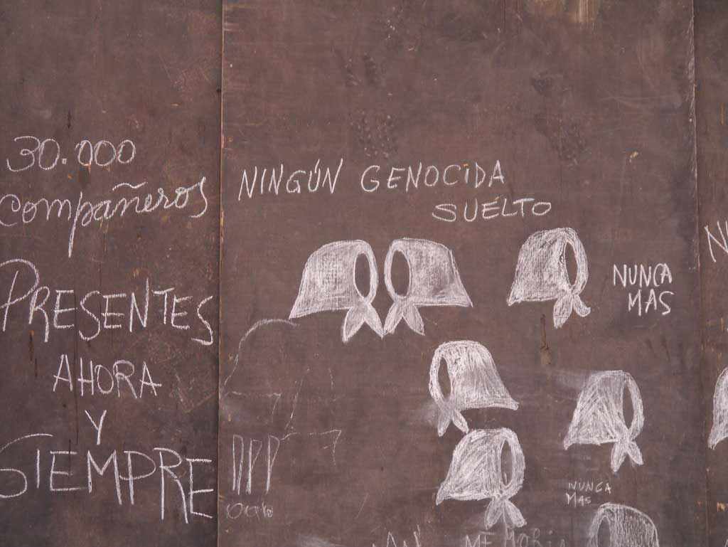 Chalk drawing on a wall that reads "Ningún Genocida Suélto"