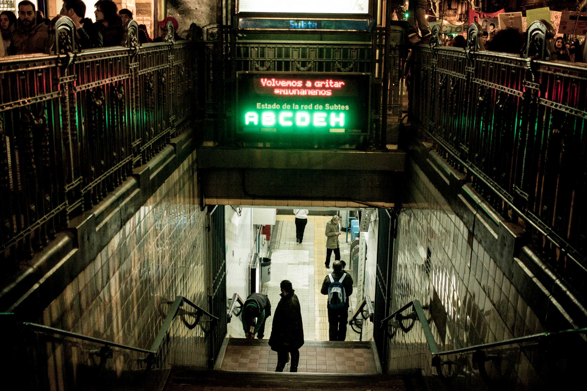 People exiting a subway station, with a neon sign that reads "not one more".
