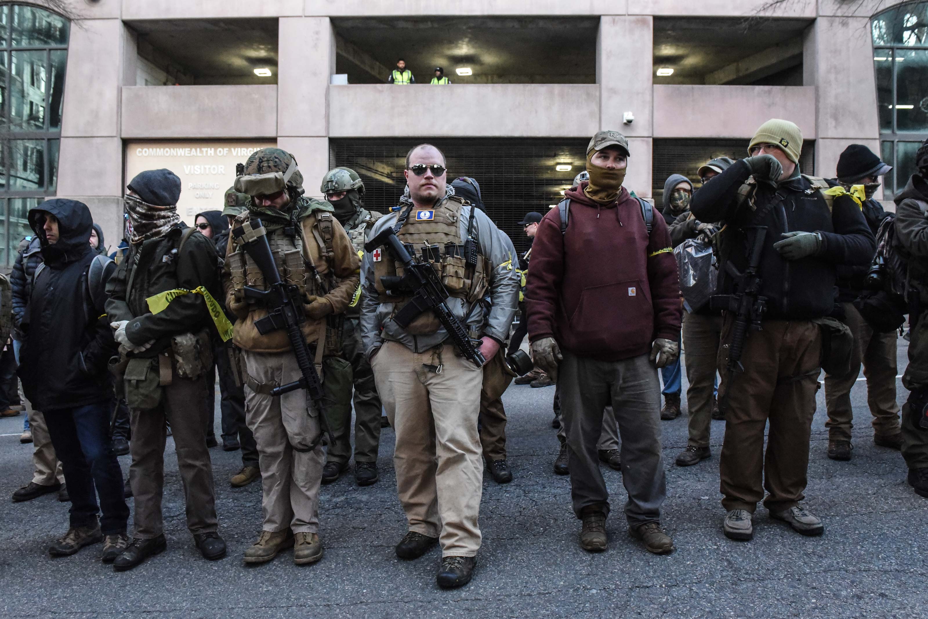 An armed militia group stand outside a tall building